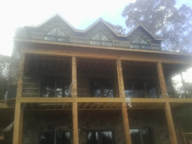 Dormers and porch framing on a large log home under construction — Roof Coating work by our crew in Atwood