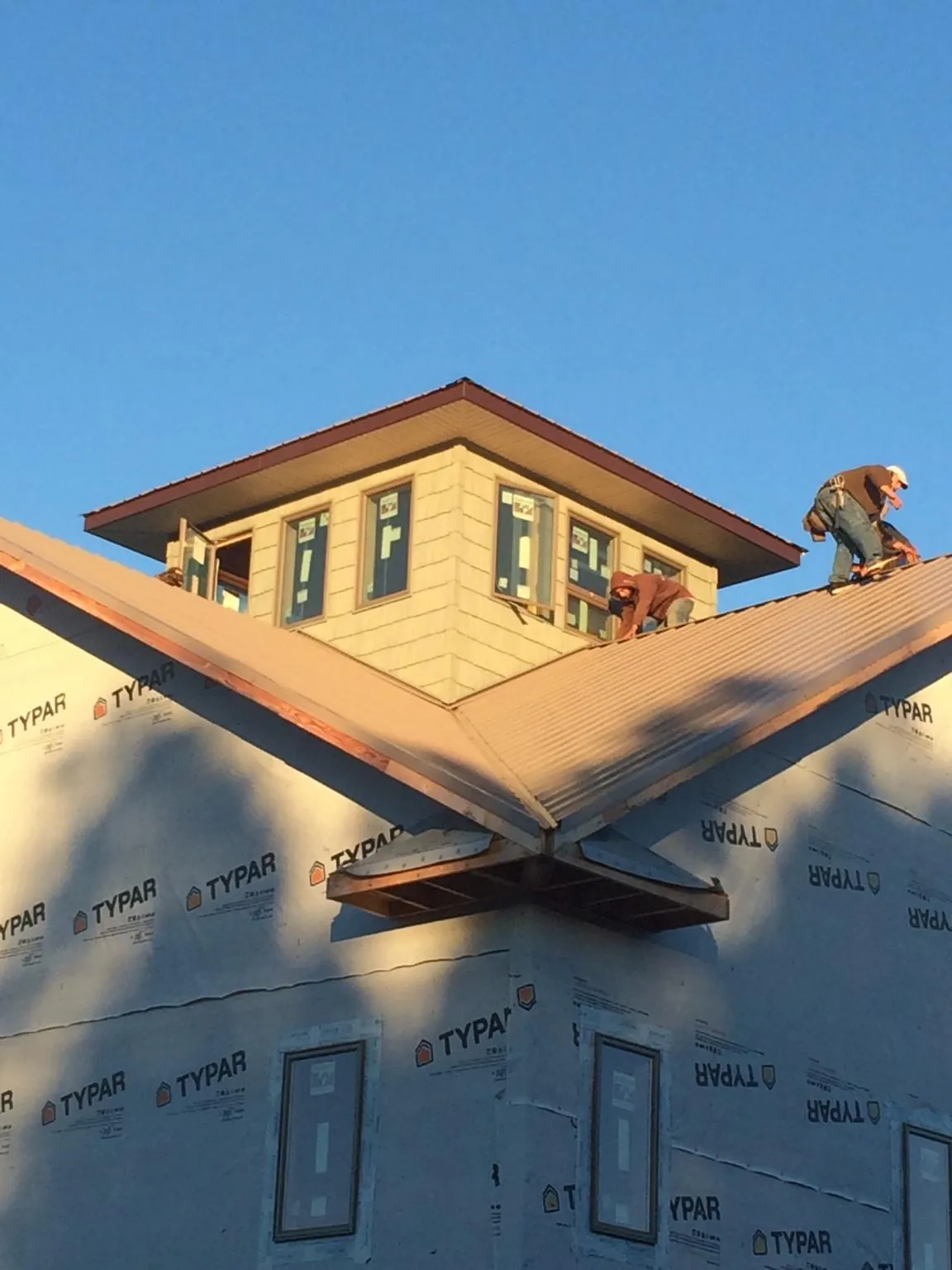 Roofers working around a rooftop cupola on a new metal roof at sunset — Roof Waterproofing in Atwood by Roofing Brothers